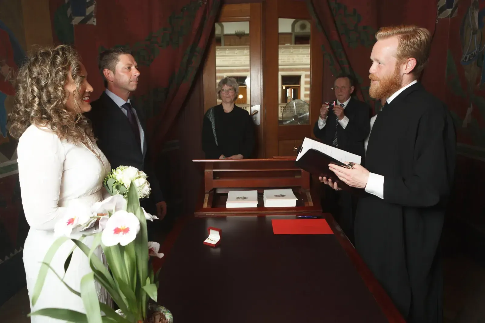 A bride slips the wedding ring onto the groom's finger at a civil ceremony