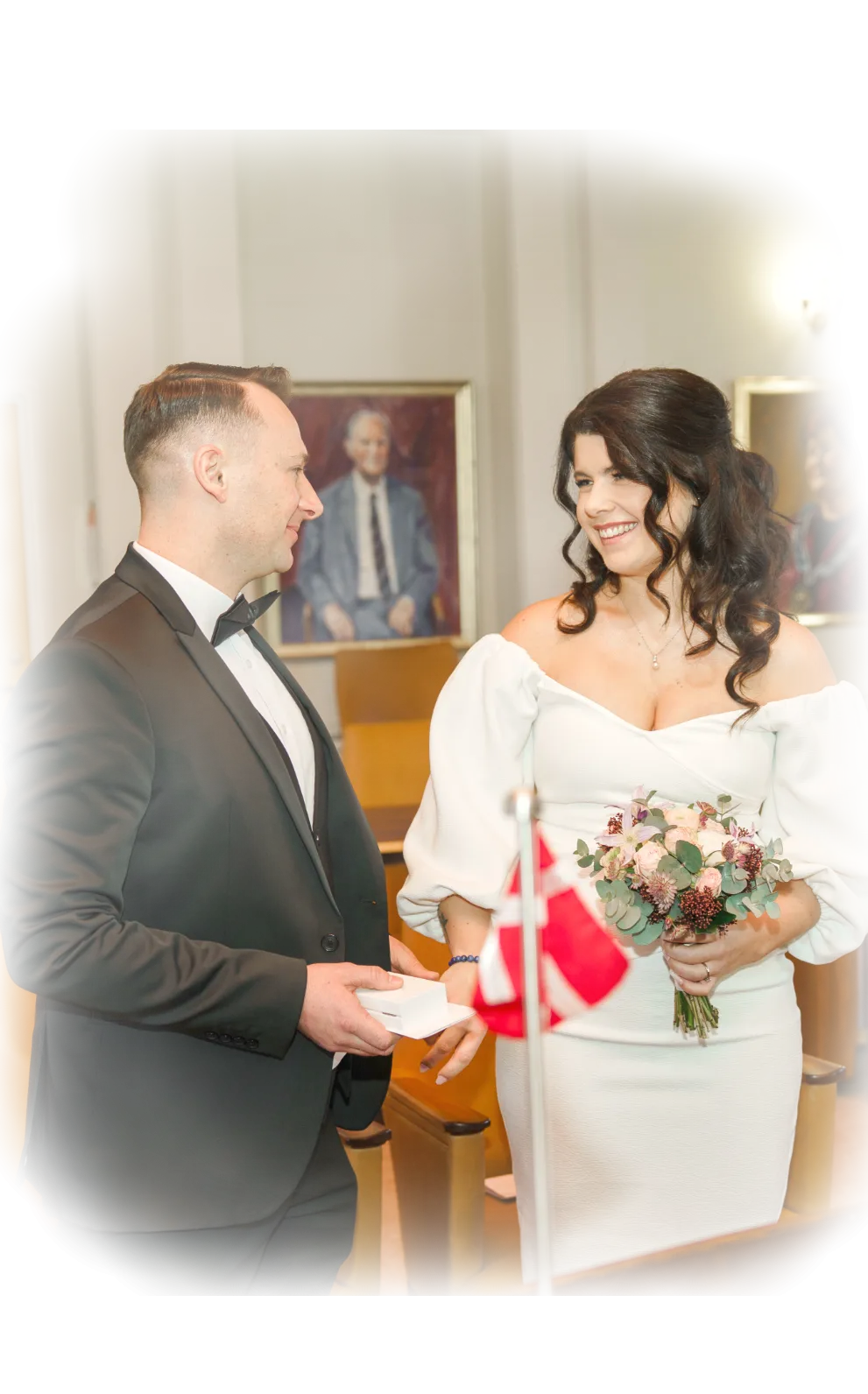 Eine Braut im Hochzeitskleid und der Bräutigam im Anzug, bei in den mittleren Jahren, haben sich gerade das Ja-Wort gegeben in dänischem Standesamt