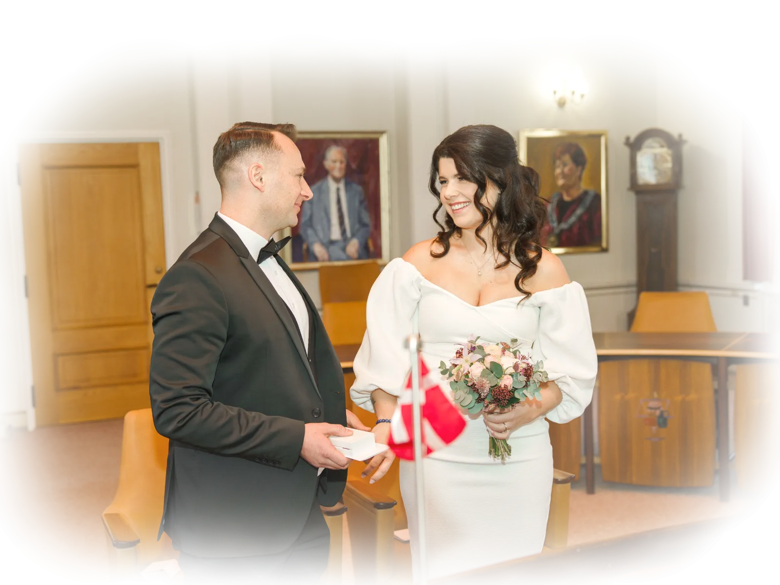 A bride in a wedding dress and the groom in a suit, both middle-aged, have just exchanged wedding vows at a Danish registry office